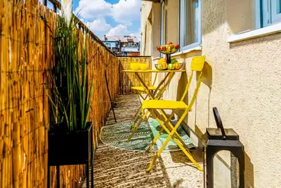 a balcony with yellow chairs and a table and a fence at Sunny Apartments with Terrace & River View Old Town in Belgrade
