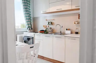 a kitchen with white cabinets and a sink and a table at Sunny Apartments with Terrace & River View Old Town in Belgrade