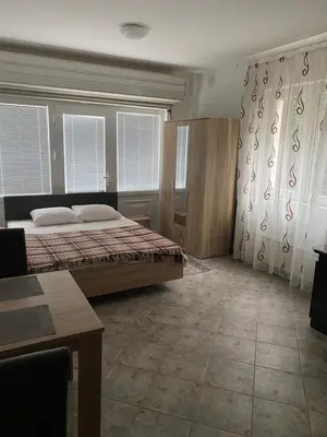 a bedroom with a bed and a table and windows at Rooms Jajinci in Belgrade