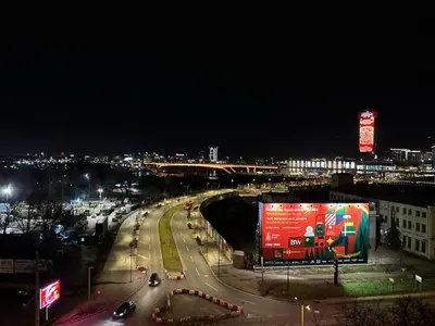 a busy city street at night with a large billboard at Nest in Sajmište