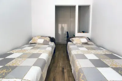 two beds in a room with white walls and wood floors at Apartment 32 in Belgrade