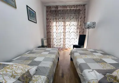 a bedroom with two beds and a chair and a window at Apartment 32 in Belgrade