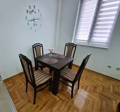 a dining room table with chairs and a clock on the wall at Tami in Belgrade