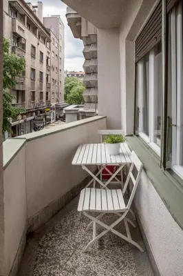a bench and a table on a balcony with a window at ZIGZAG Belgrade in Belgrade