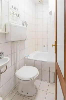 a white bathroom with a toilet and a bath tub at Downtown nest in Belgrade
