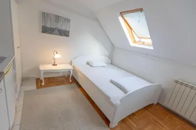 a small room with a white bed and a table at Downtown nest in Belgrade