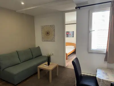 a living room with a green couch and a bedroom at Apartments and Rooms L E F T RIVER Belgrade in Belgrade