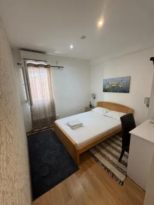 a bedroom with a bed and a desk and a window at Apartments and Rooms L E F T RIVER Belgrade in Belgrade