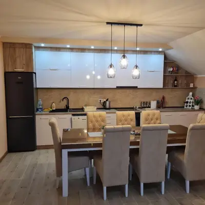 a kitchen with a wooden table and a dining room at Apartman Dalmacija in Ečka