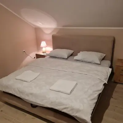 a large white bed with two white towels on it at Apartman Dalmacija in Ečka