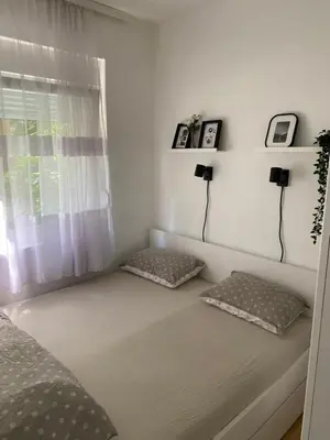 a bed with two pillows in a bedroom with a window at Urban Oasis Apartment in Sajmište
