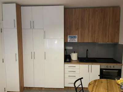a kitchen with white cabinets and a wooden table at Urban Oasis Apartment in Sajmište