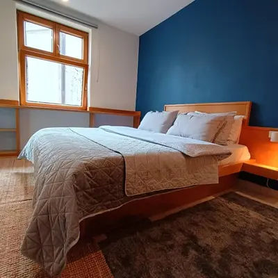 a bedroom with a large bed with a blue wall at On The Terrace La Vida Joy Mansard Top Kitchen in Belgrade