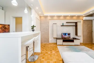 a kitchen with white cabinets and a tv in a room at Fontana Studio in Belgrade