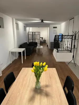 a vase of yellow flowers on a table in a living room at GardenGateStudio in Belgrade