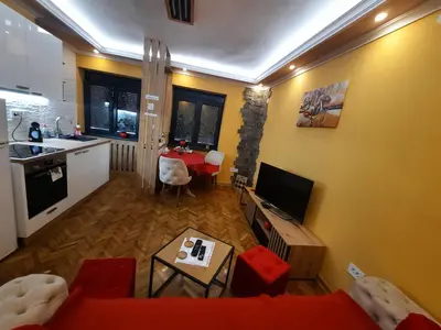 a living room with a red couch and a kitchen at G&S apartment in Novi Beograd