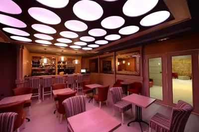 a restaurant with wooden tables and chairs and a circular ceiling at Hotel Hedonic in Belgrade