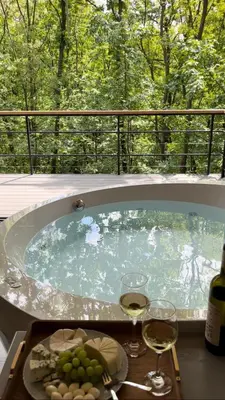a hot tub with wine glasses and a tray of food at Chado Belgrade in Belgrade
