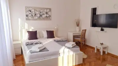 a white bed in a room with a desk and a tv at All In One Studio in Belgrade