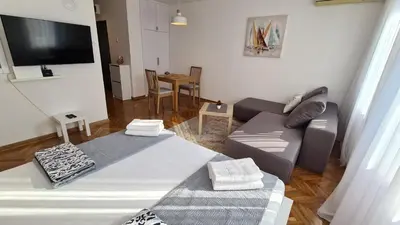 a living room with a couch and a flat screen tv at All In One Studio in Belgrade