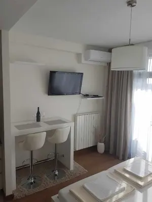 a living room with a table and a tv on the wall at All in One Belgrade Waterfront in Sajmište