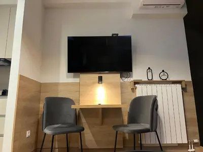 a room with a table with two chairs and a television at Belgrade Waterfront Lux Studio Apartment in Belgrade