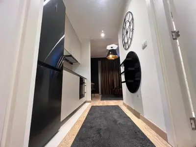 a hallway with a black refrigerator and a clock on the wall at Belgrade Waterfront Lux Studio Apartment in Belgrade