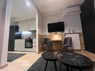 a living room with a table and chairs and a kitchen at Belgrade Waterfront Lux Studio Apartment in Belgrade
