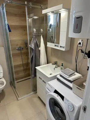 a bathroom with a shower and a washing machine at Apartman Uno Lux in Novi Grad