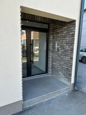 an entrance to a brick building with glass doors at Apartman Uno Lux in Novi Grad