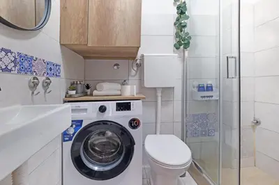 a small bathroom with a washing machine and a toilet at Theater Apartment in Vračar (historical)