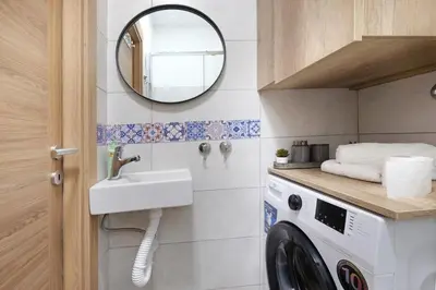 a bathroom with a washing machine and a mirror at Theater Apartment in Vračar (historical)
