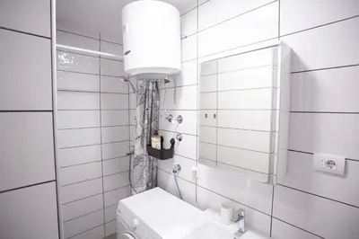 a white tiled bathroom with a toilet and a mirror at Apartment Lea in Belgrade