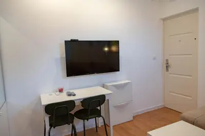 a small room with a table and a tv on the wall at AV Smart Apartment in Pančevo