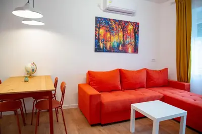 a living room with a red couch and a table at AV Smart Apartment in Pančevo