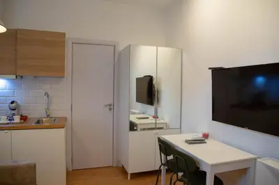 a small kitchen with a table and a tv on a wall at AV Smart Apartment in Pančevo