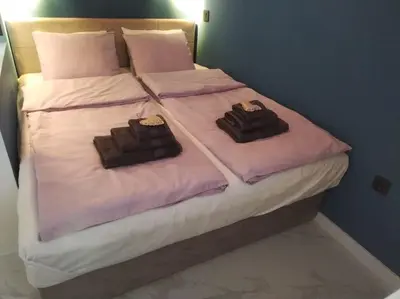 two towels on a bed with purple sheets at Sweet Home in Belgrade