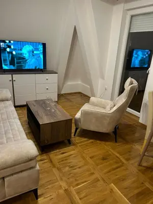 a living room with a tv and two chairs and a table at Apartman Comfort Beograd in Belgrade