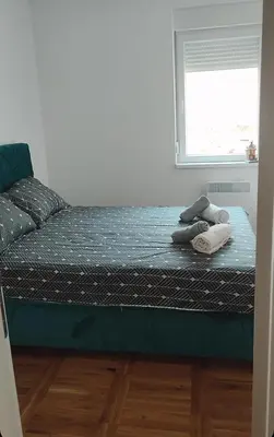 a bed with two pillows and a window in a room at Apartman Comfort Beograd in Belgrade