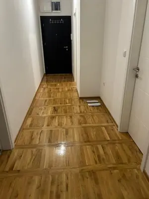a hallway with a wooden floor and a black door at Apartman Comfort Beograd in Belgrade