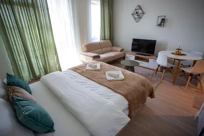 a bedroom with a large bed and a living room at inJoy in Sajmište