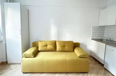 a yellow couch in a room with a kitchen at Apartman Tašmajdan in Belgrade