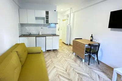 a living room with a yellow couch and a kitchen at Apartman Tašmajdan in Belgrade