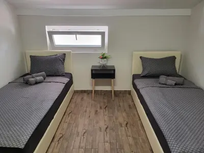 two beds in a small room with a table at Guesthouse Ožegović in Belgrade