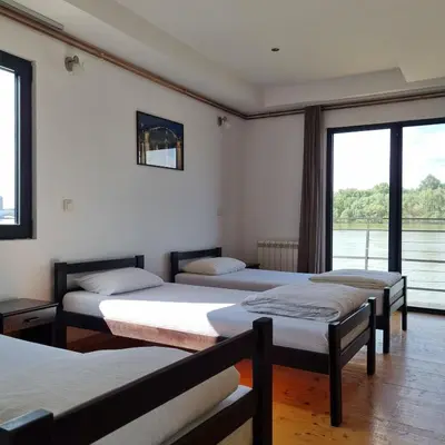 a room with three beds and a large window at B&B Botel Charlie in Belgrade