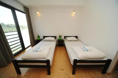 two beds in a room with large windows at B&B Botel Charlie in Belgrade