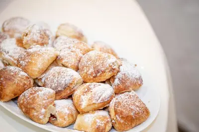 a pile of powdered donuts on a white plate at Atera Business Suites in Belgrade
