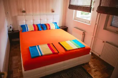 a bedroom with a bed with colorful pillows and a window at Apartment Arena White in Belgrade