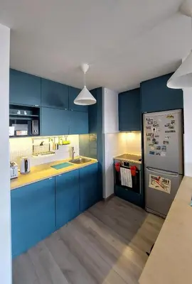 a kitchen with blue cabinets and a refrigerator at Cozy studio apartment in Belgrade