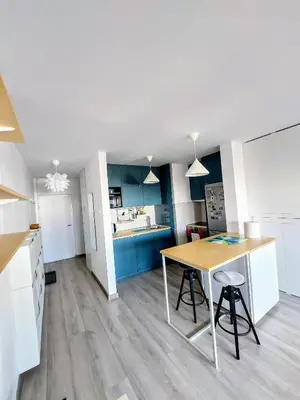 a kitchen with white cabinets and a wooden table at Cozy studio apartment in Belgrade